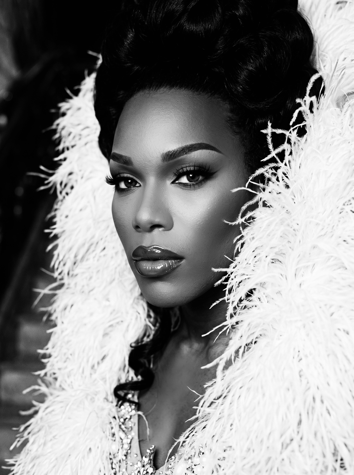 Black-and-white close portrait of Dee Jiles framed by white feathers