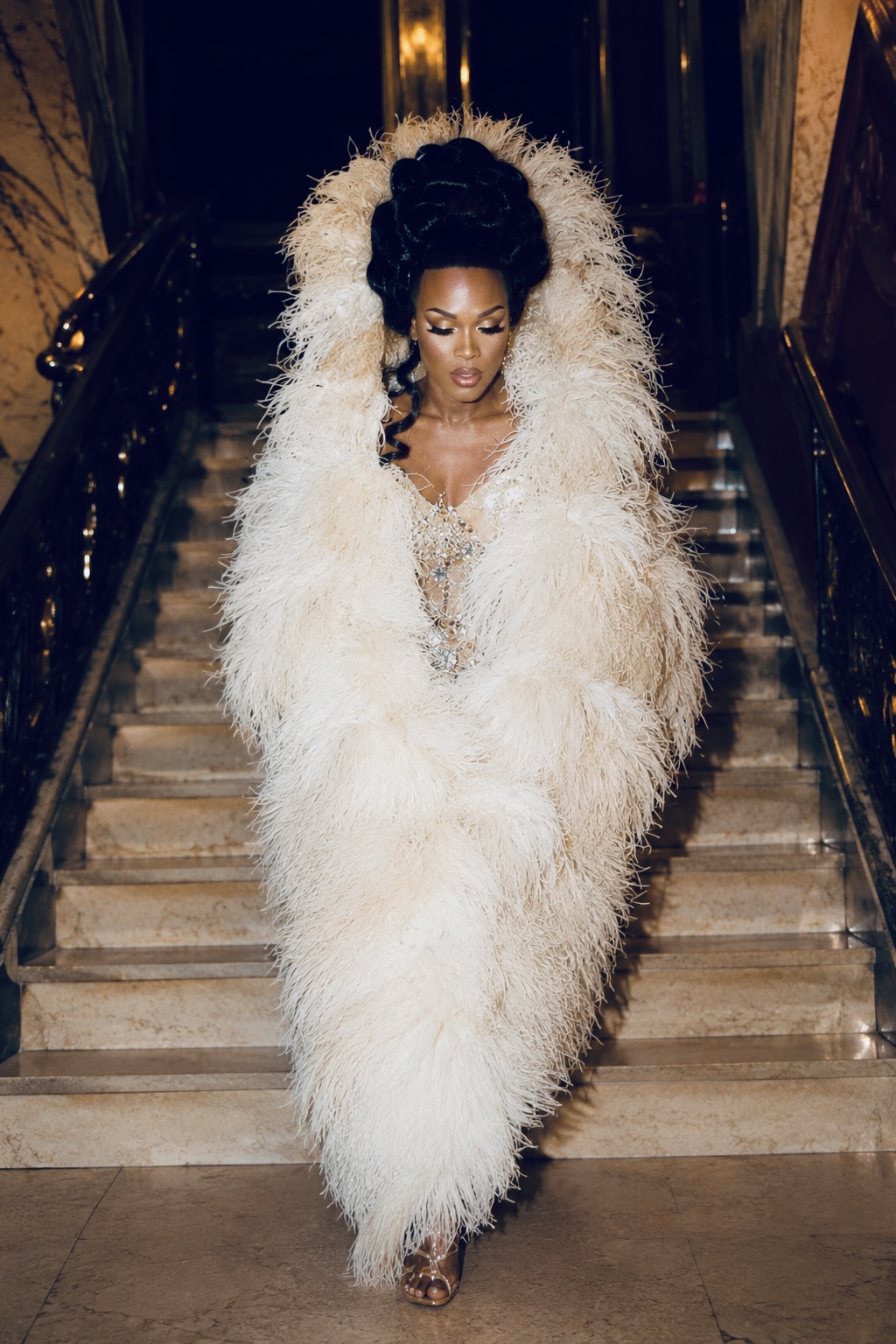Dee Jiles descending a staircase in a white feather coat